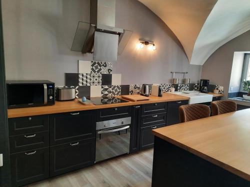 a kitchen with black cabinets and a counter top at L'INATTENDU Vue imprenable,clim,parking avec borne de recharge, ménage inclus in Montaigu