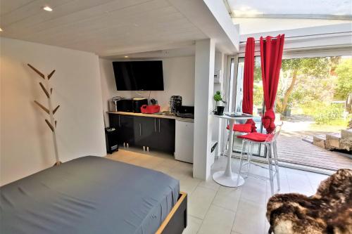 a bedroom with a bed and a kitchen with a table at Les Terrasses Levantines in Île du Levant