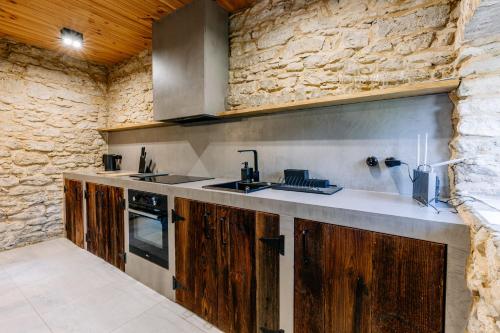 a kitchen with wooden cabinets and a stone wall at AleChatki Roztocze in Huta Lubycka