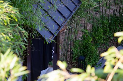 a fence with a blue umbrella in a garden at Tomonoya Hotel & Ryokan Daecheon in Boryeong