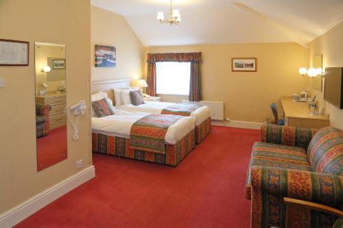 a hotel room with two beds and a desk at Saxonville Hotel in Whitby