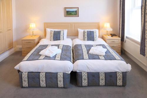 two beds in a bedroom with two lamps and towels at Saxonville Hotel in Whitby