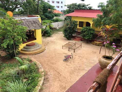 an empty yard with a yellow house and a playground at Magharibi House in Nungwi