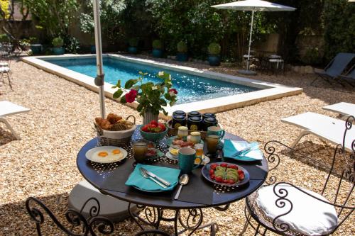 une table avec de la nourriture dessus à côté d'une piscine dans l'établissement Le Jardin de Mazan, à Mazan