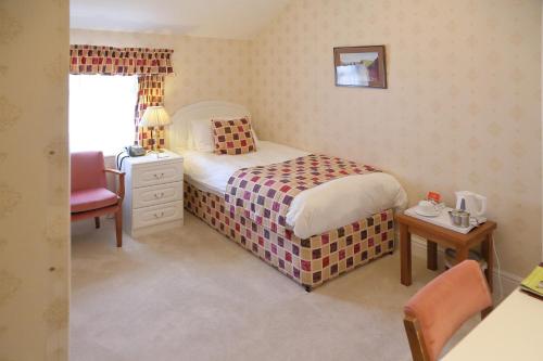 a small bedroom with a bed and a chair at Saxonville Hotel in Whitby