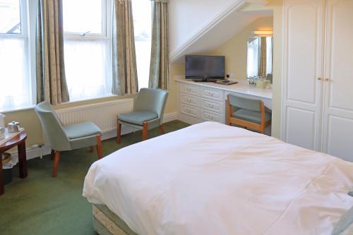 a bedroom with a bed and two chairs and a desk at Saxonville Hotel in Whitby