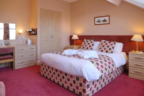 a bedroom with a large bed with a desk and a desk at Saxonville Hotel in Whitby