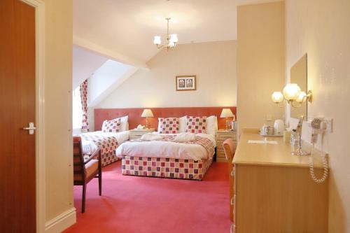 a bedroom with two beds and a desk in a room at Saxonville Hotel in Whitby