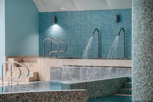 a bathroom with two faucets and a tub with water at Leśny Apartament Nad Zalewem in Kielce