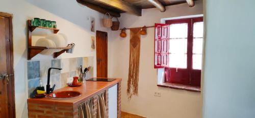 a kitchen with a sink and a red window at La Morada de Higuera in Higuera de la Sierra