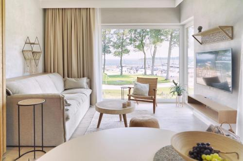 een woonkamer met een bank en een groot raam bij Good Morning Sunshine - Nautica Resort Apartment in Giżycko
