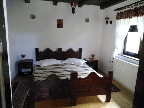 a bedroom with a wooden bed with white walls and a window at Casuta din Valea Regilor in Grădiştea de Munte