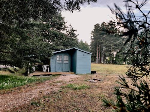 a blue shed in a field with a chair at Camping Zvejnieksēta in Pāvilosta