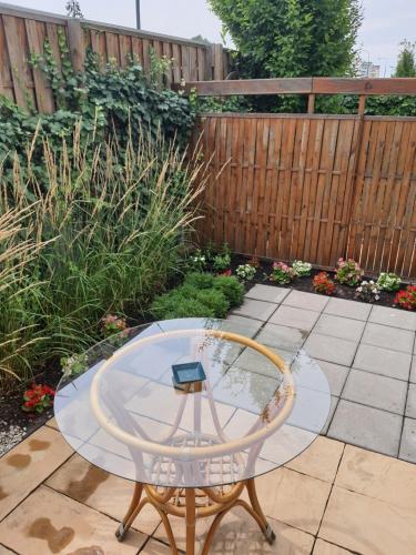 a glass table and a chair in a garden at Apartamenty Dom Saski 10 minut od Centrum Warszawy in Warsaw