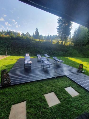 een groep stoelen en tafels op een houten terras bij Cabana Brazilor in Vatra Dornei