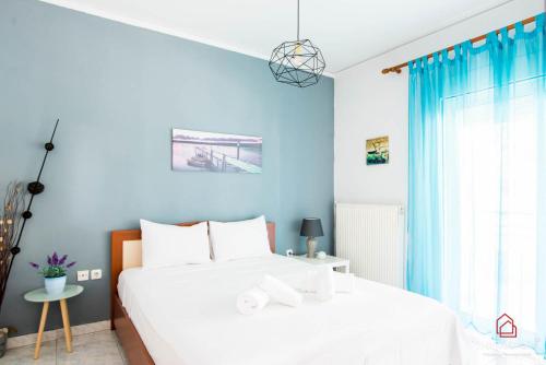 a blue bedroom with a white bed and a window at PK Luxury Apartment, feels like home in Alexandroupoli