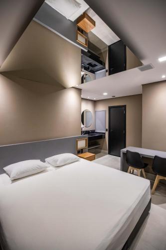 a bedroom with a large white bed and a table at Drops Motel e Hotel Campinas in Campinas