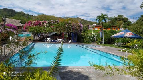 a swimming pool with white chairs and flowers at Meson Hondano in Honda