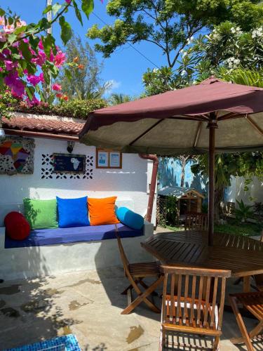 a couch with colorful pillows sitting under an umbrella at Luciano & Grace Apartments in Watamu
