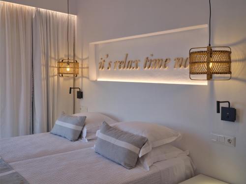 a white bedroom with a bed with two pillows at Infinity sea view hillside villa with private pool in Parikia