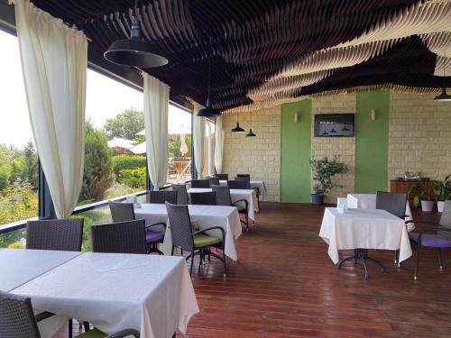 a restaurant with white tables and chairs and green walls at Villa Lavanda in Vapnyarka