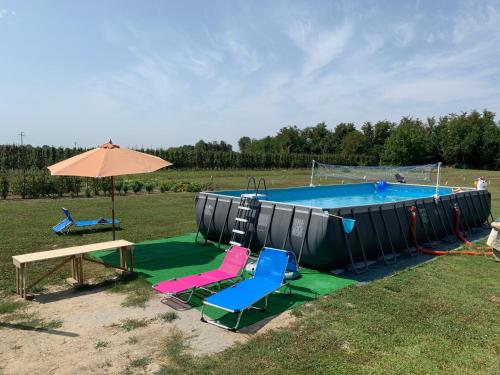 uma piscina com cadeiras, uma mesa e um guarda-sol em Borgo Tarapino em Ferrara