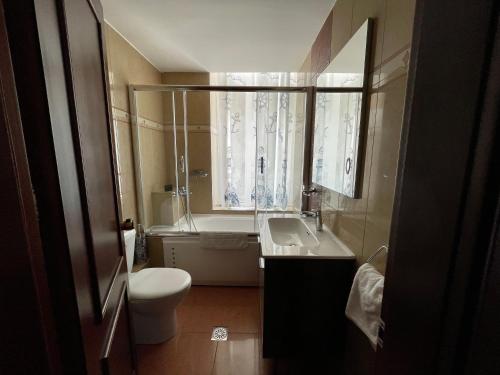 een badkamer met een wastafel, een toilet en een raam bij Poros Mood in Poros