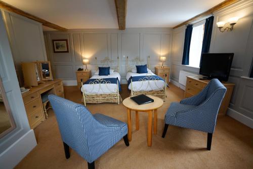 a bedroom with two beds and a table and chairs at Waveney House Hotel in Beccles