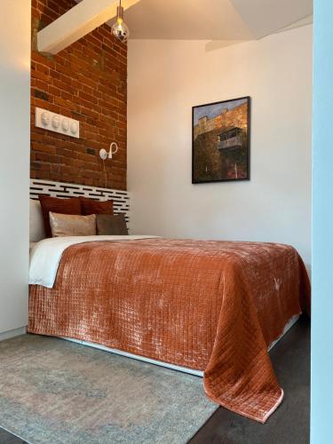 a bedroom with a large bed with a brick wall at Jolie Apartments in Kaunas