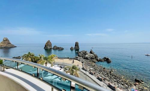 een uitzicht op een strand met rotsen in het water bij Grand Hotel Faraglioni in Acitrezza