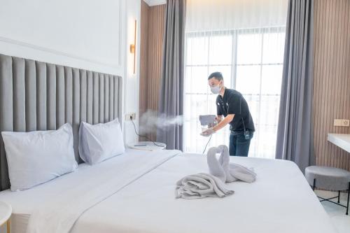 a man standing in a hotel room with a bed at Kala Hotel Semarang in Jomblang