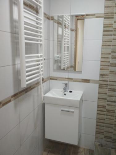 een witte badkamer met een wastafel en een spiegel bij GRÉTA APARTMAN A BALATONNÁL,CSOPAKON!!! in Csopak