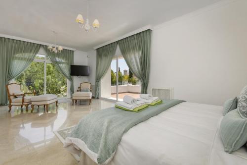 una camera con un grande letto bianco e un soggiorno di Villa Penati a San Pedro de Alcántara