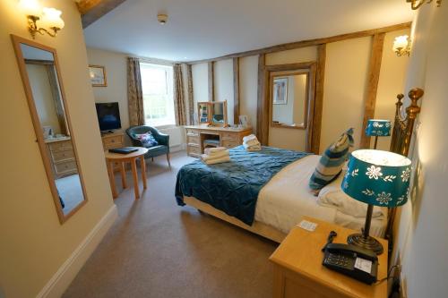 a bedroom with a bed and a desk with a lamp at Waveney House Hotel in Beccles