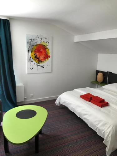 a bedroom with a bed and a green table and a painting at La maison de Cécile in Ventron