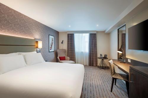 um quarto de hotel com uma cama, uma secretária e uma televisão em Leonardo Hotel Chester em Chester