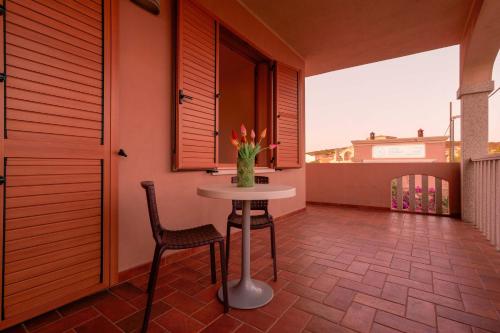 a table and chair on a balcony with a vase of flowers at Capofrascaresort in Sant' Antonio di Santadi