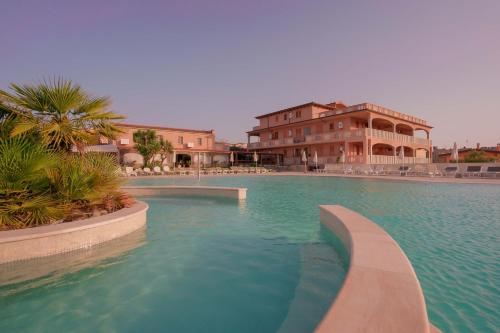 a swimming pool in front of a large building at Capofrascaresort in Sant' Antonio di Santadi