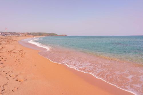 a beach with footprints in the sand and the ocean at Capofrascaresort in Sant' Antonio di Santadi