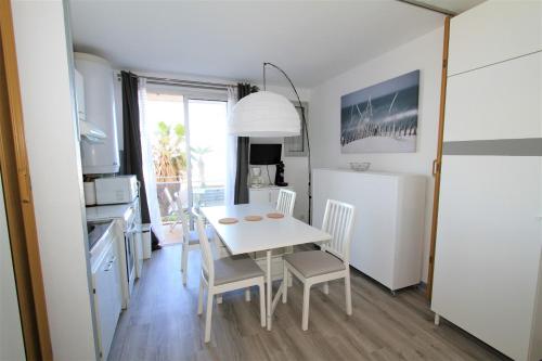 une cuisine et une salle à manger avec une table et des chaises blanches dans l'établissement Studio vue mer, à Canet