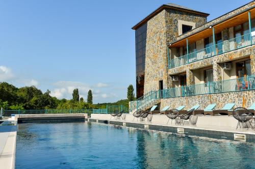a swimming pool with chairs and a building at Tskaltubo Epic Hotel & Spa in Tskaltubo
