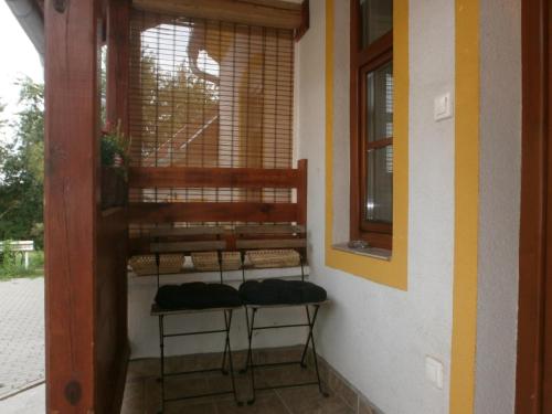 un porche con 2 taburetes en una habitación con ventana en Ninszianna Apartman, en Hegyhátszentjakab
