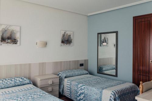 a hotel room with two beds and a mirror at Pensión Amaia in Vitoria-Gasteiz