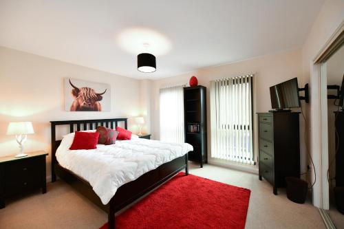 a bedroom with a large bed with a red rug at West Portland View Apartment A in Troon