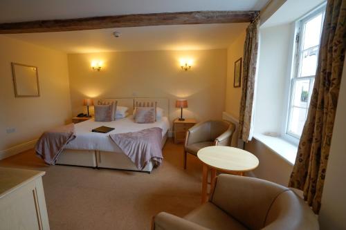 a bedroom with a bed and a table and chairs at Waveney House Hotel in Beccles