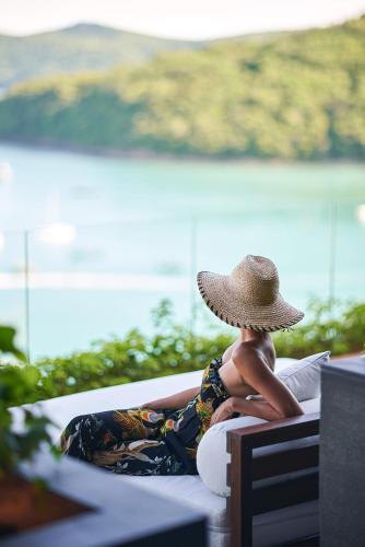 a man wearing a straw hat sitting on a bench at V Villas Phuket - MGallery Collection in Panwa Beach