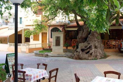 a table and chairs in front of a tree at bougainvilla in Fodele