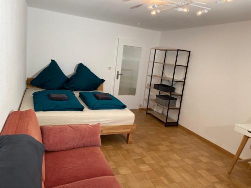菲爾斯騰費爾德布魯克的住宿－Private Wohnung in Fürstenfeldbruck, nahe Ammersee/München/Augsburg，一间卧室配有一张带蓝色枕头的床和一张沙发。