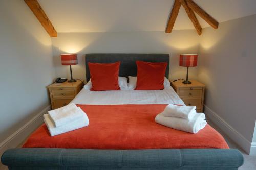 a bedroom with a bed with red pillows and two lamps at Waveney House Hotel in Beccles