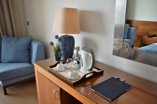 a desk in a hotel room with a table with a lamp and a mirror at Madeira Regency Cliff - Adults Only in Funchal